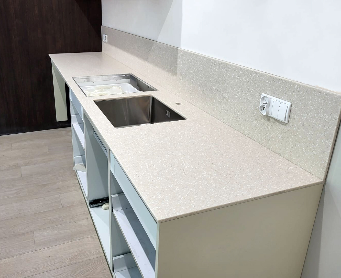 Beżowy blat z materiału solid surface (Grandex A401 Cloudy Mount) z eleganckim zlewem podwieszanym.